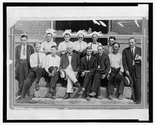 Historic black-and-white photograph of a group of men seated and standing on stone steps